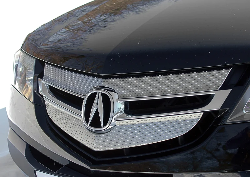 Acura logo on a silver textured grille with a glossy black hood