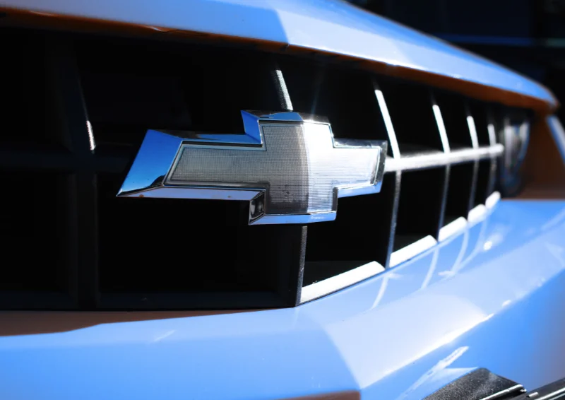 Close-up of Chevrolet bowtie badge on a light blue front grille