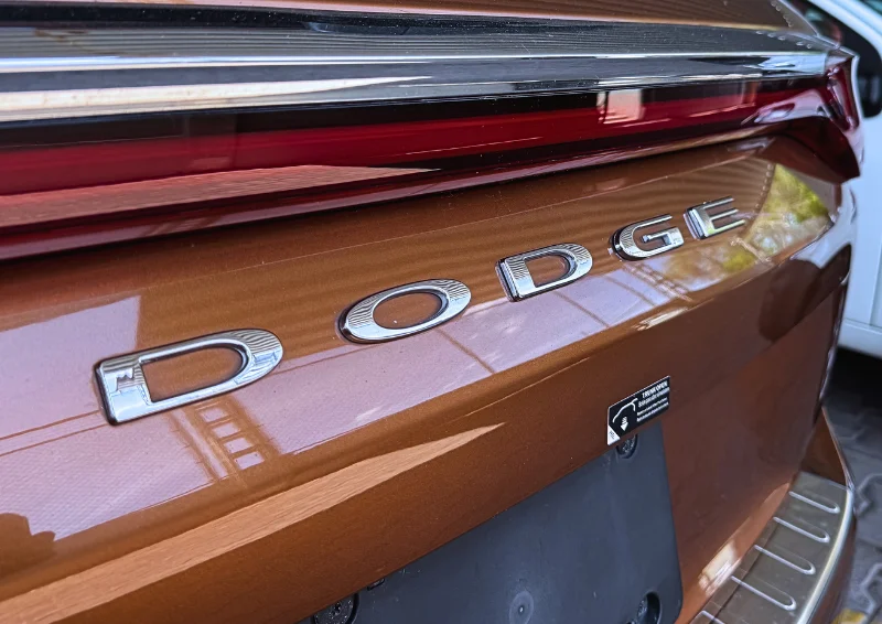 Chrome Dodge lettering on back of brown car with red tail light trim