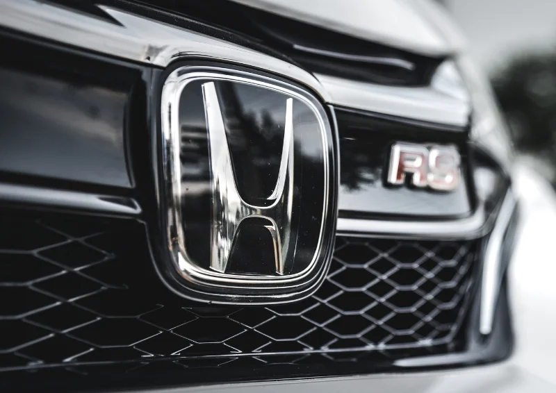 Close-up of Honda logo with RS badge on glossy black grille