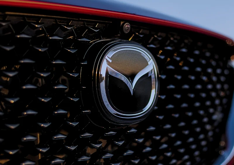 Close-up of Mazda emblem on a black diamond-patterned front grille