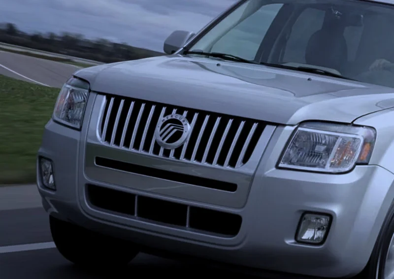 Mercury SUV driving on road with front grille and logo visible.