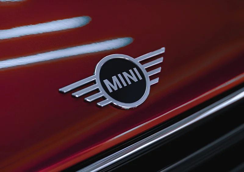 MINI emblem displayed on glossy red vehicle surface with reflection