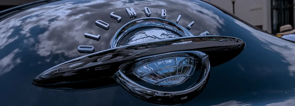 Oldsmobile trunk badge with globe emblem and reflections of sky