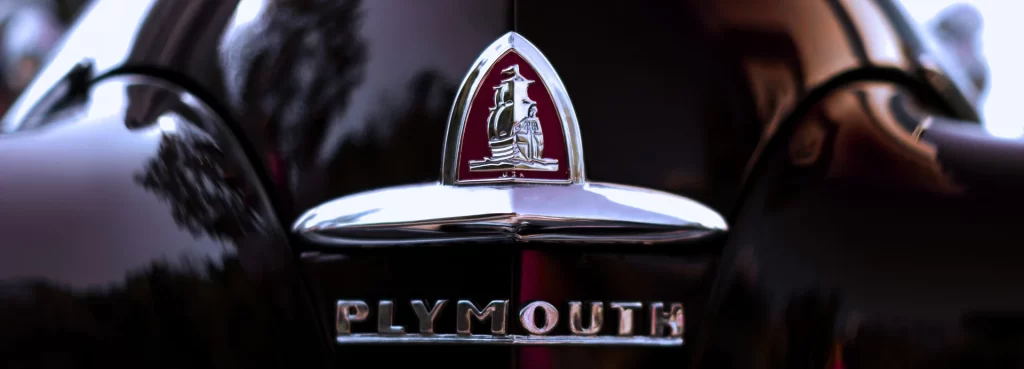 Rear badge of vintage Plymouth with red ship emblem and chrome trim