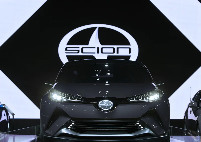 Scion concept car showcased with large logo display in background.