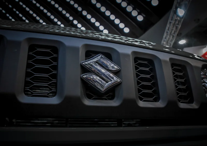 Close-up of Suzuki logo on matte black front grille with hex pattern