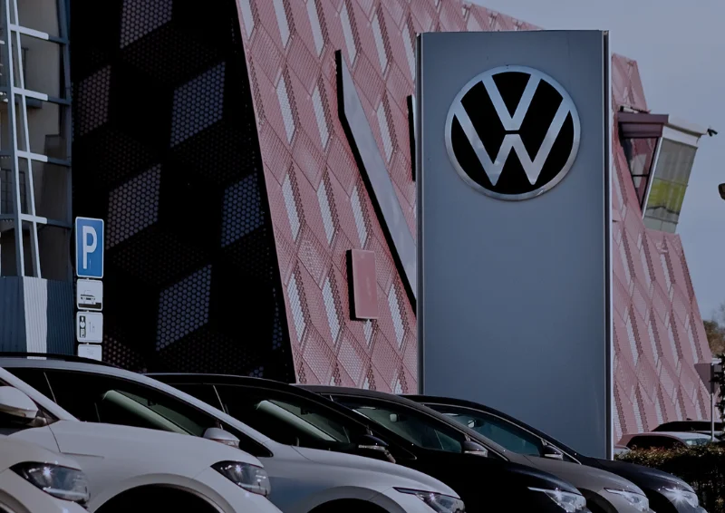 Volkswagen dealership with logo sign and parked cars along frontage